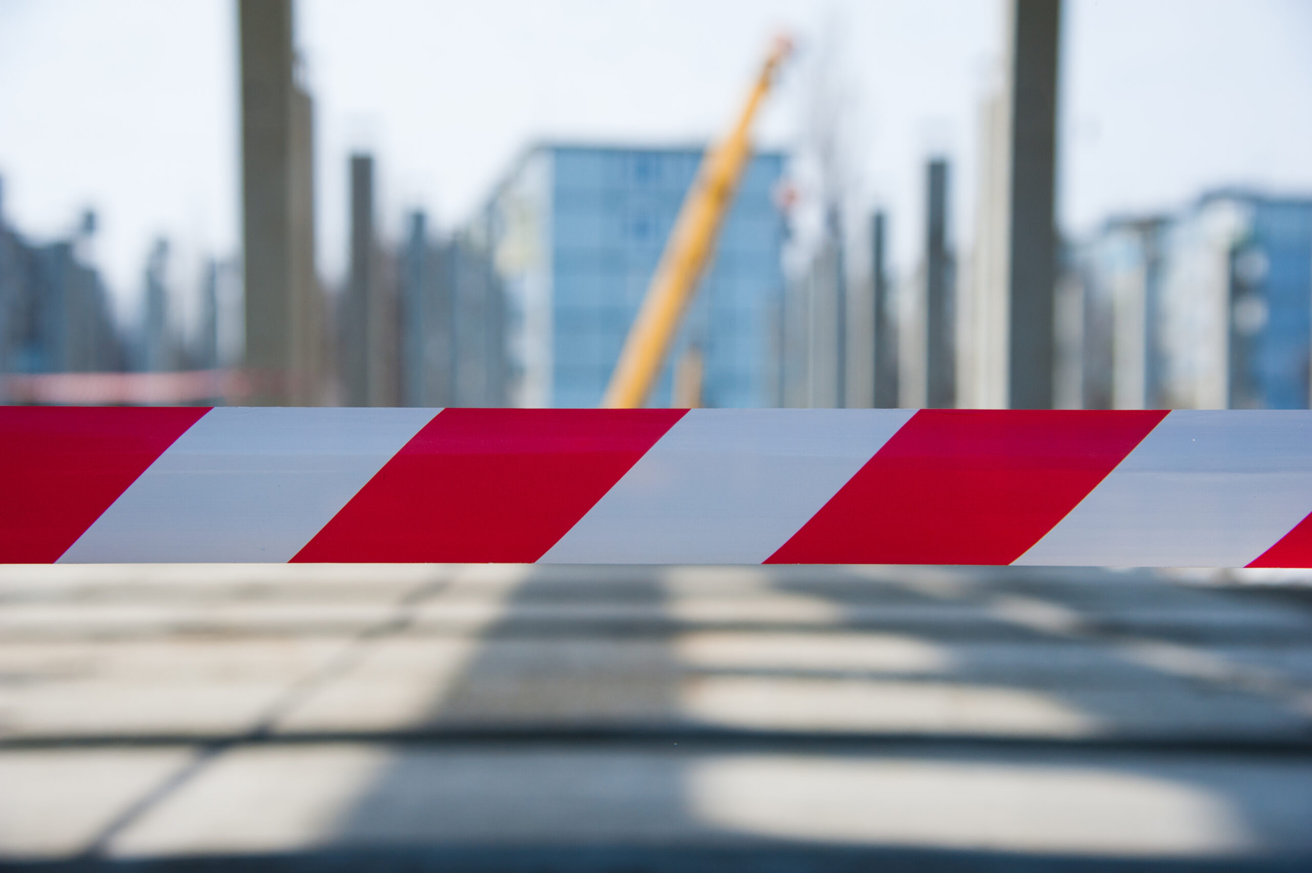 Rot-weißes Absperrband vor einer Baustelle mit Kran