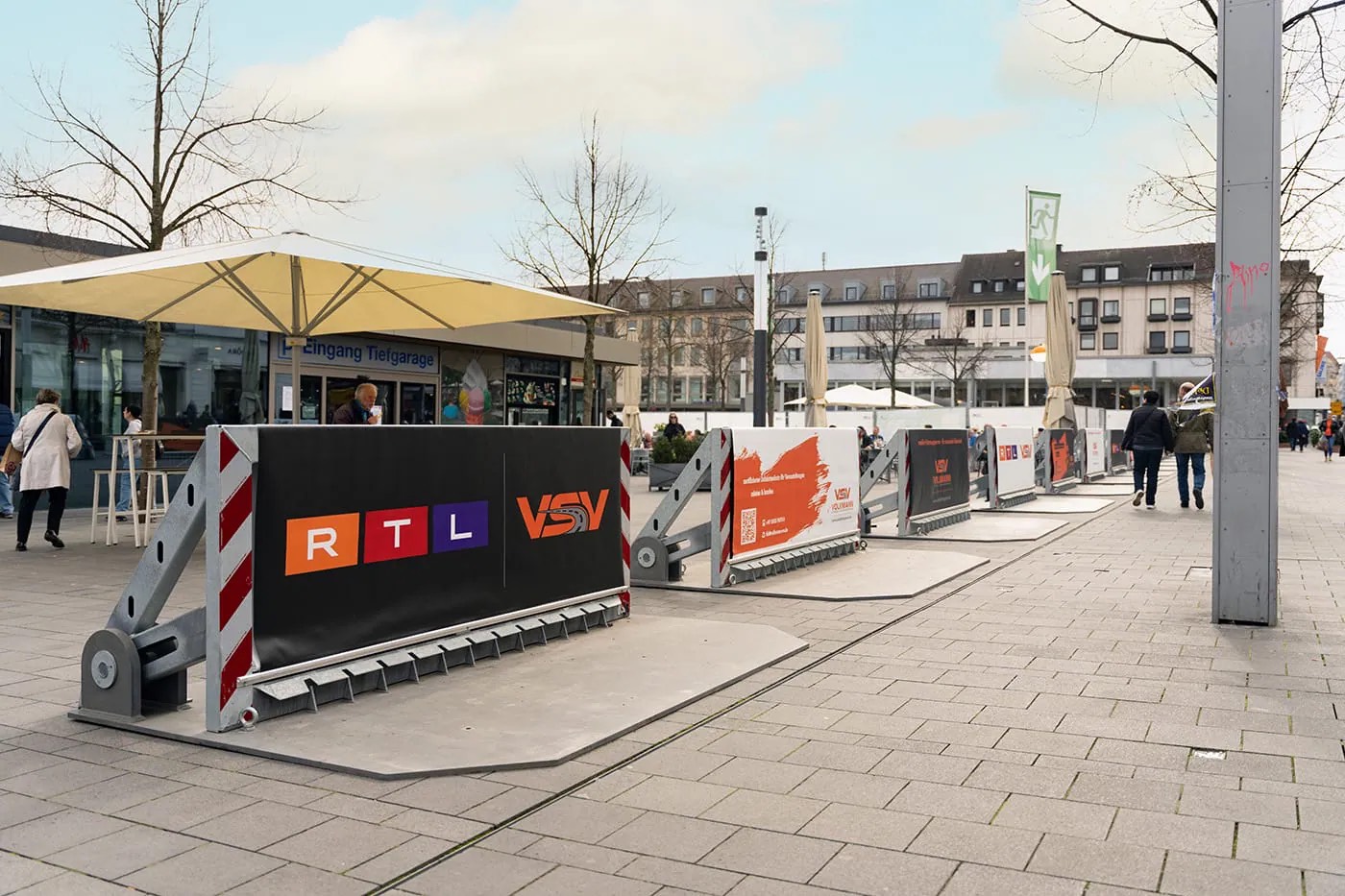 Mobile Fahrzeugsperren mit Werbebannern auf einem städtischen Platz